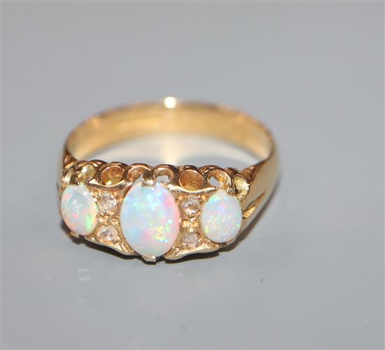 A George V 18ct gold, three stone opal and diamond chip set dress ring, size O.